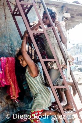 Tres niñas ven la televisión de un vecino desde la entrada de una casa de Dharavi.